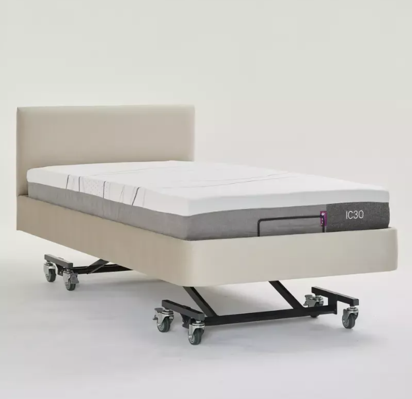 An adjustable electric motorized bed frame with a beige upholstered base and headboard, shown with a white mattress on a black wheeled platform against a light gray studio background.